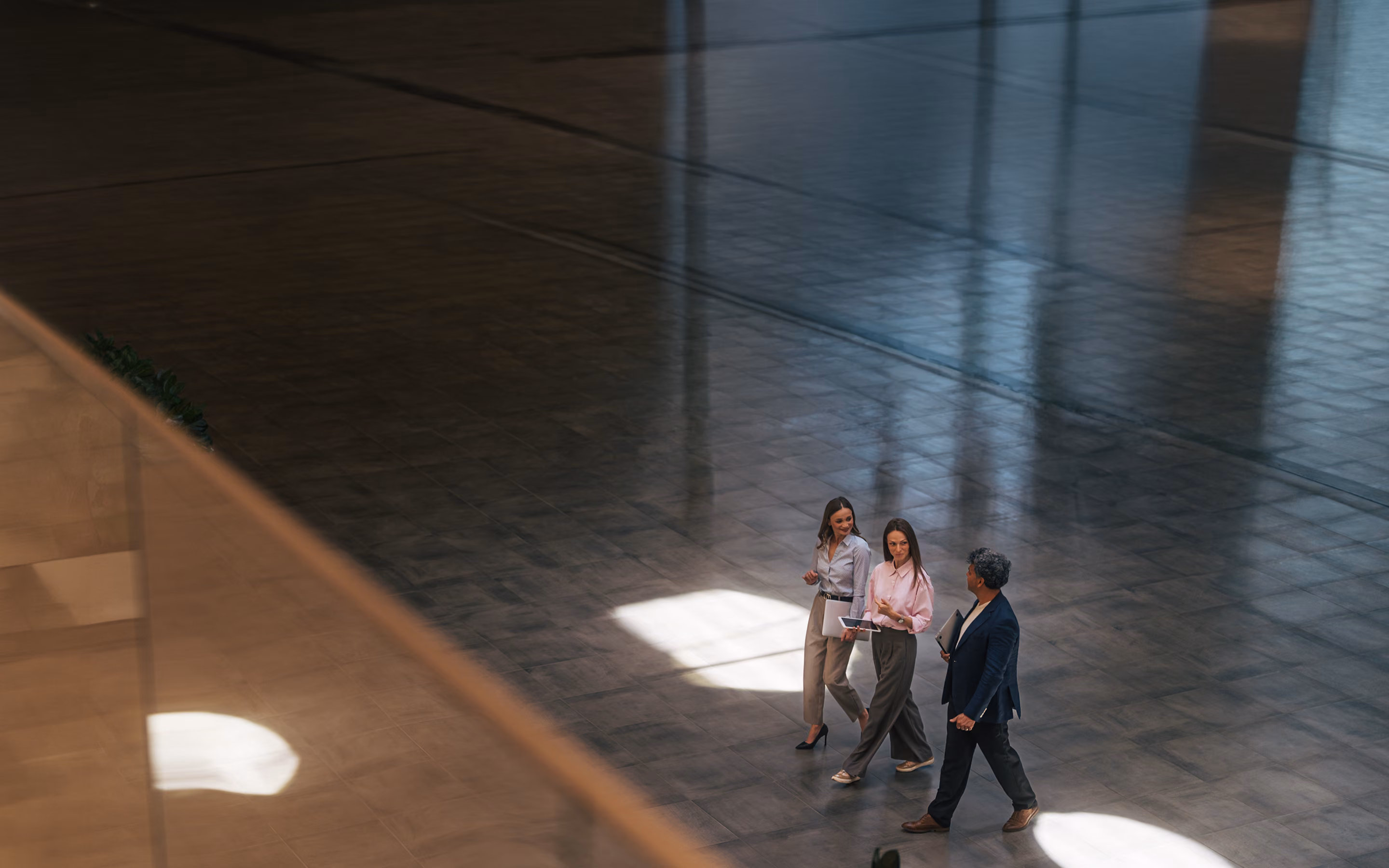 Three professionals walking through a grand, dimly lit lobby.